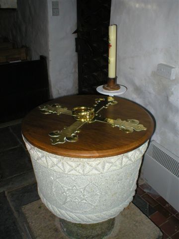 A fine round white stone font with a brass bound wooden cover