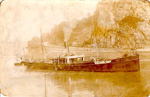 A slender single funnel steam vessel slowly navigatesup the River Avon