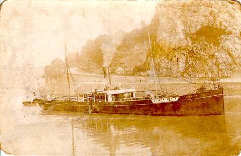 A slender single funnel steam vessel slowly navigatesup the River Avon