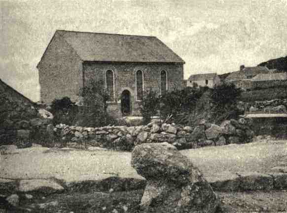 An austere four square chapel with stone hedge surround